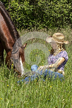 Cowgirl with her horse in the grass.