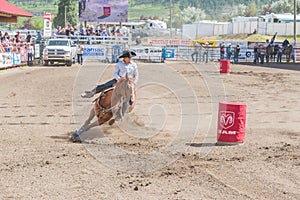 Cowgirl and horse gallop around second barrel at barrel racing event