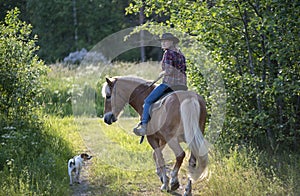 Cowgirl horseback riding in forest