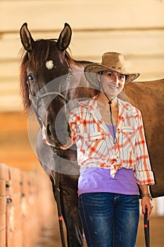 Cowgirl standing next to brown horse friend