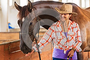 Cowgirl standing next to brown horse friend