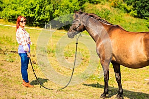 Cowgirl standing next to brown horse friend