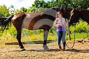 Cowgirl standing next to brown horse friend