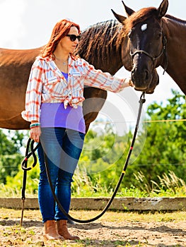 Cowgirl standing next to brown horse friend