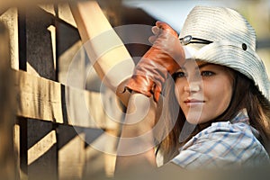 Cowgirl in stetson next to wooden fence