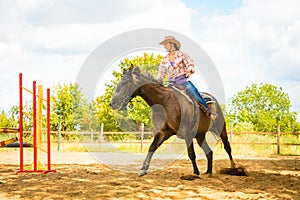 Cowgirl in western hat doing horse jumping