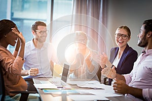 Coworkers applauding a colleague during a meeting