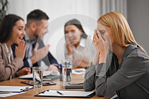 Coworkers bullying their colleague at workplace in office