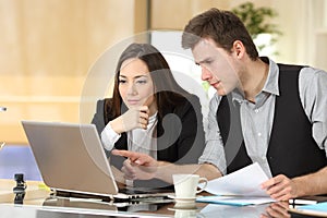 Coworkers checking laptop content together at office photo