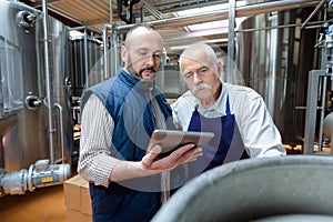 coworkers discussing over digital tablet in factory