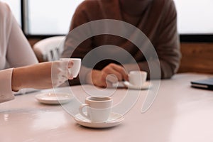 Coworkers enjoying coffee during break in cafe, focus on cup. Space for text