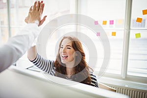 Coworkers giving high-five in creative office