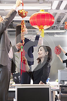 Coworkers hanging decorations in office for Chinese new year