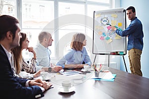 Coworkers looking at colleague giving presentation