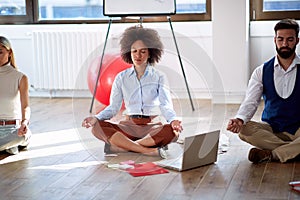 Coworkers practicing meditation at work. Coworkers sitting on the floor with computer and work notes