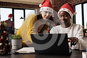 Coworkers in santa hats checking report