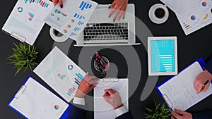 Coworkers sitting at office desk and discussing financial documents