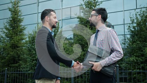 Coworkers successful men shaking hands outdoors saying good-bye then leaving