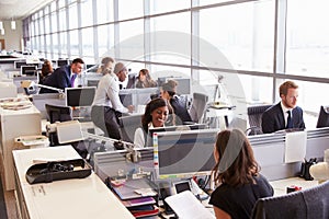 Coworkers at their desks in a busy, open plan office