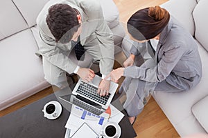 Coworkers using laptop together sitting on sofa