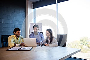 Coworkers working around a table with a laptop