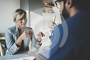 Coworkers working process at home.Young blonde woman working together with bearded colleague man at modern home office