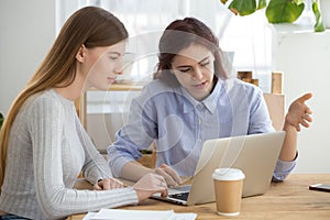 Coworkers working together on laptop, mentor training intern with computer