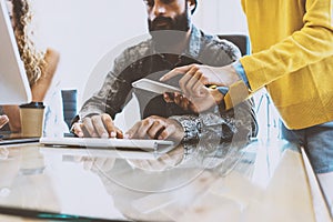 Coworking process in a sunny office.Man working on computer at the wood table.Woman wearing yellow pullover and touching