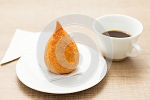 Coxinha is a deep fried food, traditional in Brazil. Snack, pepper sauce and coffee. Bar food. Selective focus.