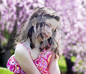 Coy little girl sitting in a garden