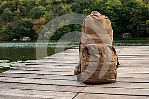 Coyote color tactic backpack on wooden pier on bank of river.