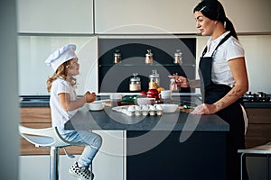 Cozy atmosphere. Mother with her daughter are preparing food on the kitchen