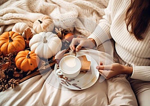 Cozy autumn at home,Woman drinking tasty pumpkin coffee on bed. A cozy way of life . AI Generated