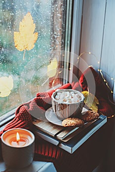 cozy autumn morning at home. Hot cocoa with marshmallows and candle on window in rainy cold day