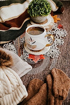 Cozy autumn still life with cup of hot black coffee. knitted hat and scarf on wooden background