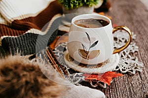 Cozy autumn still life with cup of hot black coffee. knitted hat and scarf on wooden background