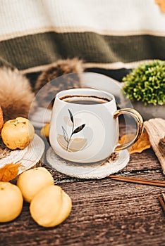 Cozy autumn still life with cup of hot black coffee. knitted hat and scarf on wooden background