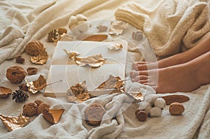 Cozy Autumn winter evening , warm woolen socks. Woman is lying feet up on white shaggy blanket and reading book