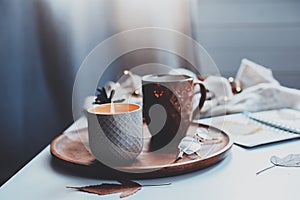 cozy autumn or winter morning at home. Still life details with cup of tea, candle, sketch book with herbarium and warm sweater