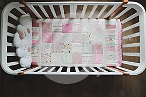 Cozy baby cot with pink patchwork blanket. Baby bedding. Baby crib, close up. Textile for children nursery. Nap and sleep time