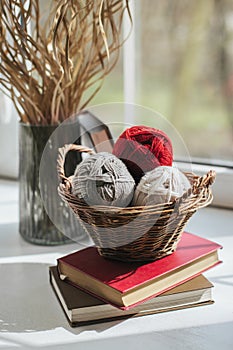 Cozy balls of yarn for hand knitting in the basket near the window. Background for handmade and slow homelife