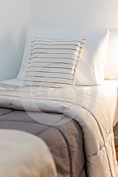 Cozy bed with brown and light beige duvets and white pillows