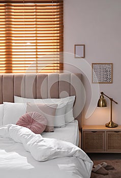 Cozy bed with soft linens in light room