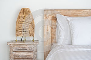 Cozy bed with wicker night lamp on bedside table at modern house interior