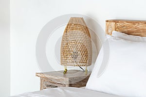 Cozy bed with wicker night lamp on bedside table at modern house interior