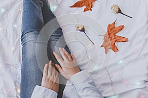 Cozy bedroom. Females relaxing at her bed in the cold autumn morning. Fall leaves and dried rose flowers. A woman dreaming and