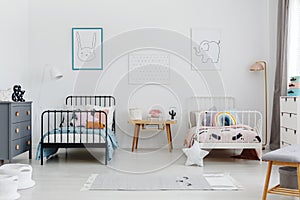 Cozy bedroom interior for siblings. Two beds, one white, one black with patterned bedding and posters of a rabbit and elephant on