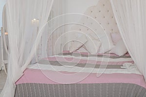 Cozy bedroom in light pastel colors, a large four-poster bed with pillows. Scandinavian simplicity design. Eco loft