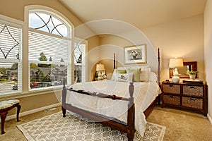 Cozy Beige bedroom with vaulted ceiling and elegant Victorian style bed.