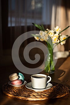 Cup of coffee on wooden table, vase with flowers.
